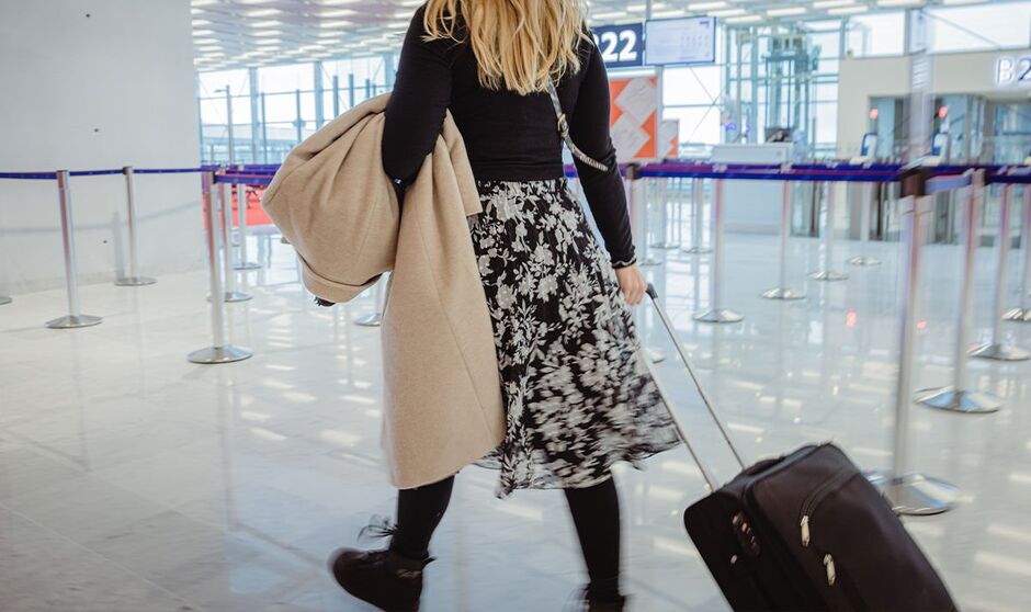 Femme avec manteau et valise à l'aéroport