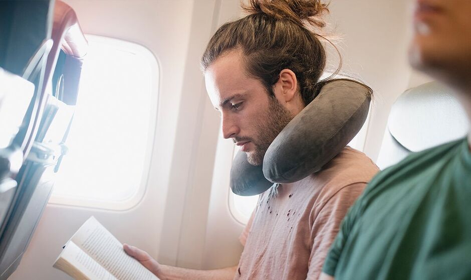 Homme avec oreiller cervical dans l'avion
