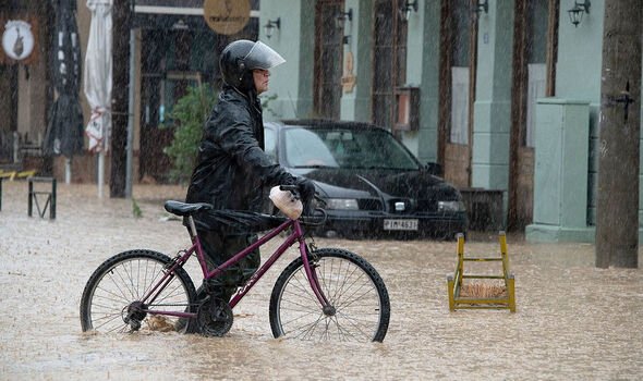 Un homme avec son vélo dans une rue inondée