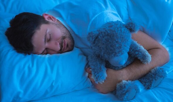 Un homme dort avec un ours en peluche