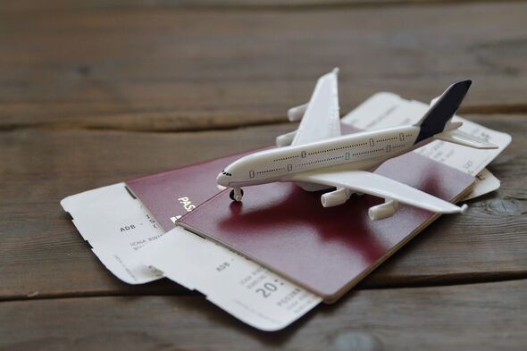 Un avion jouet posé sur deux passeports remplis de billets