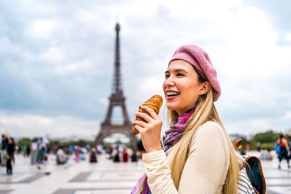Femme mangeant un croissant devant la Tour Eiffel à Paris