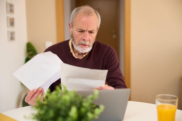 Homme plus âgé regardant la paperasse et utilisant un ordinateur portable