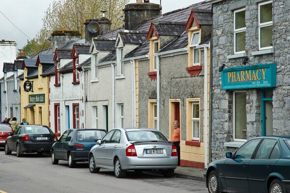 Cong, comté de Mayo, Irlande - 4 juin 2006 : une résidente locale regarde par la porte de sa maison sur un bloc de construction constitué de Cong 