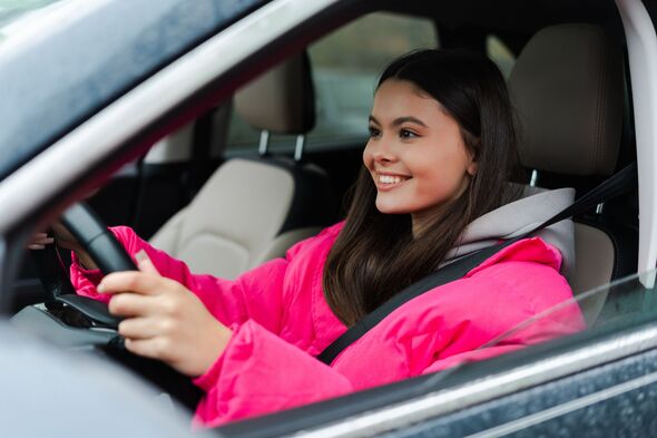 Heureuse jeune femme adulte conduisant une voiture en voyage, souriant et se sentant libre