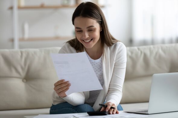 Souriante jeune belle femme lisant un papier bancaire