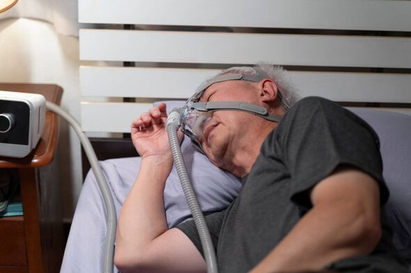 Une personne se repose dans un lit, utilisant un appareil CPAP
