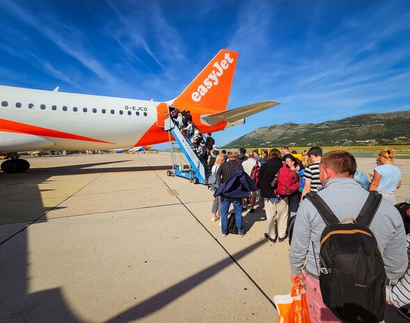   passagers faisant la queue à l'extérieur par une journée ensoleillée pour monter à bord d'un vol easyJet