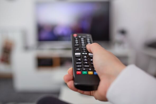 Regarder la télévision et utiliser la télécommande. Main avec la télécommande pour changer de chaîne ou ouvrir des applications sur Smart TV