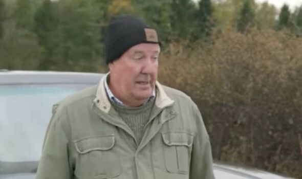 Un homme en manteau vert parle et se tient près d'une voiture Un homme en manteau vert parle et se tient près d'une voiture