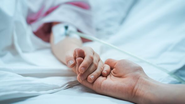 Récupération d'un petit enfant allongé dans le lit d'hôpital endormi, la mère lui tient la main pour la réconforter. Concentrez-vous sur les mains. Moment émotionnel en famille.