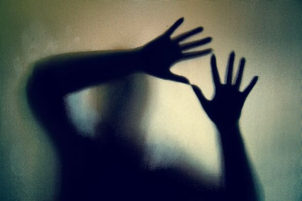 Silhouette de femme avec les mains pressées contre la vitre